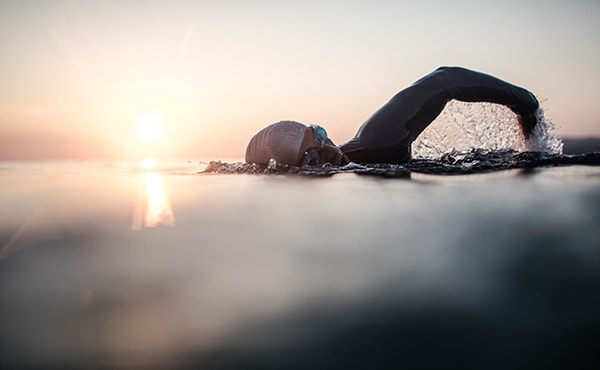 person swimming outside at sunrise