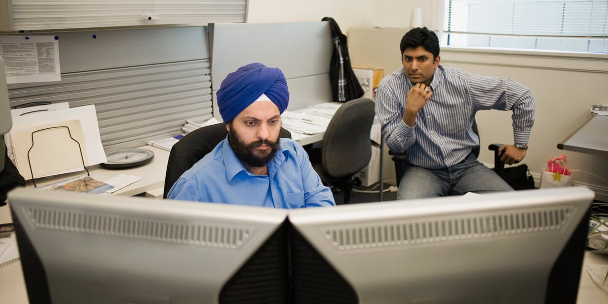two men in office looking at computer monitor