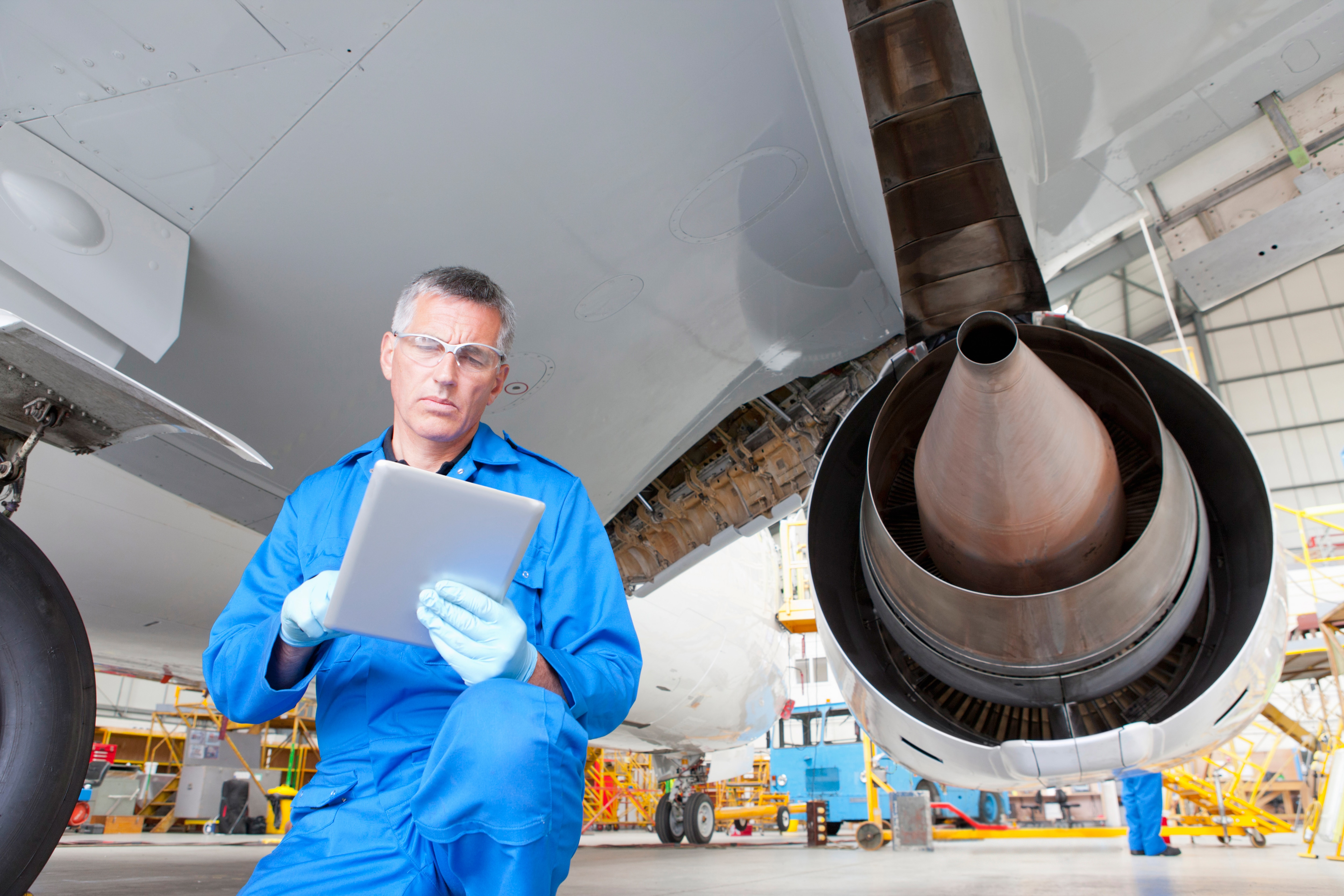 Contractor looking at a tablet under and airplane