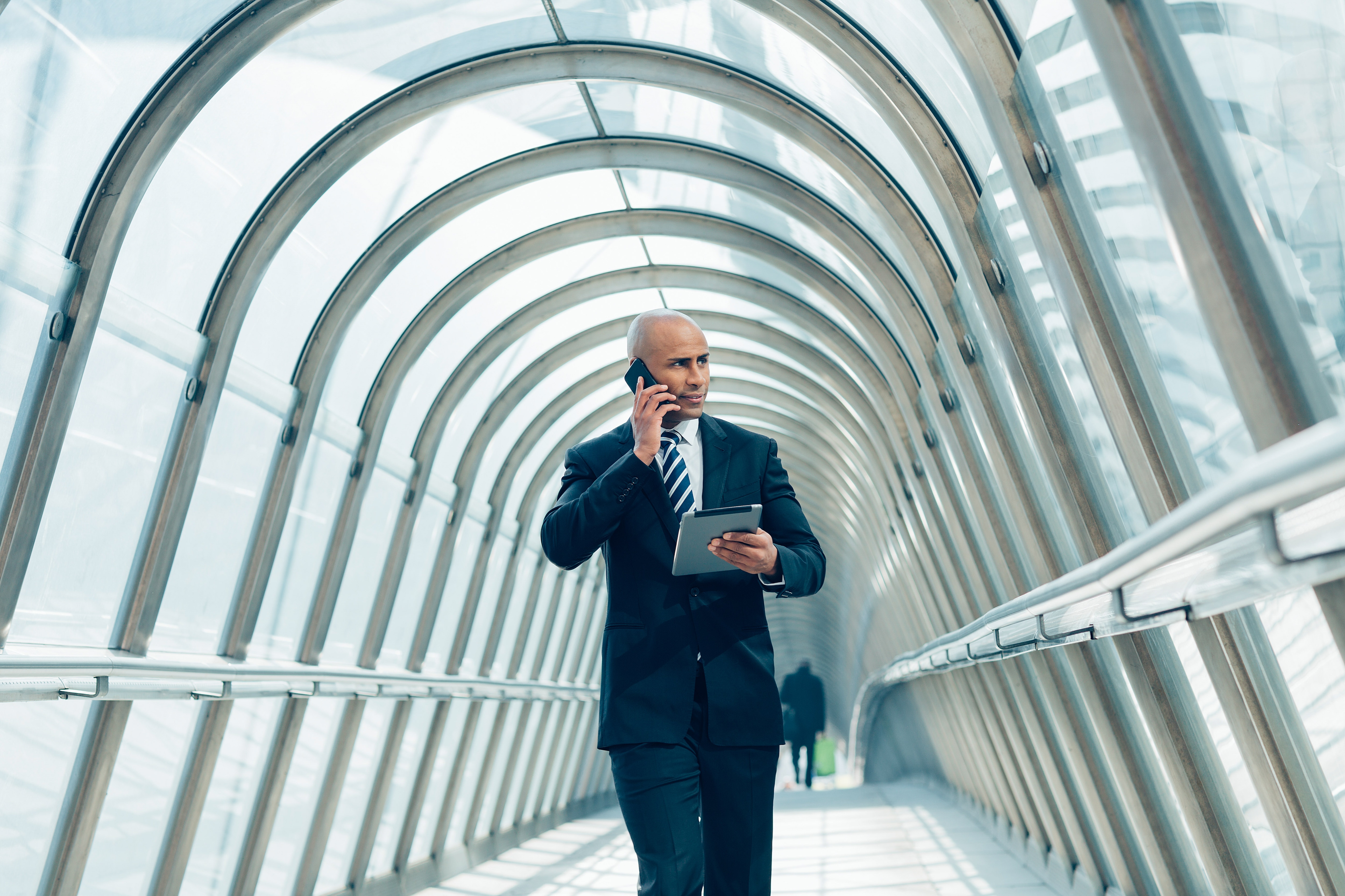A man walking down the tunnel in a suit on the phone