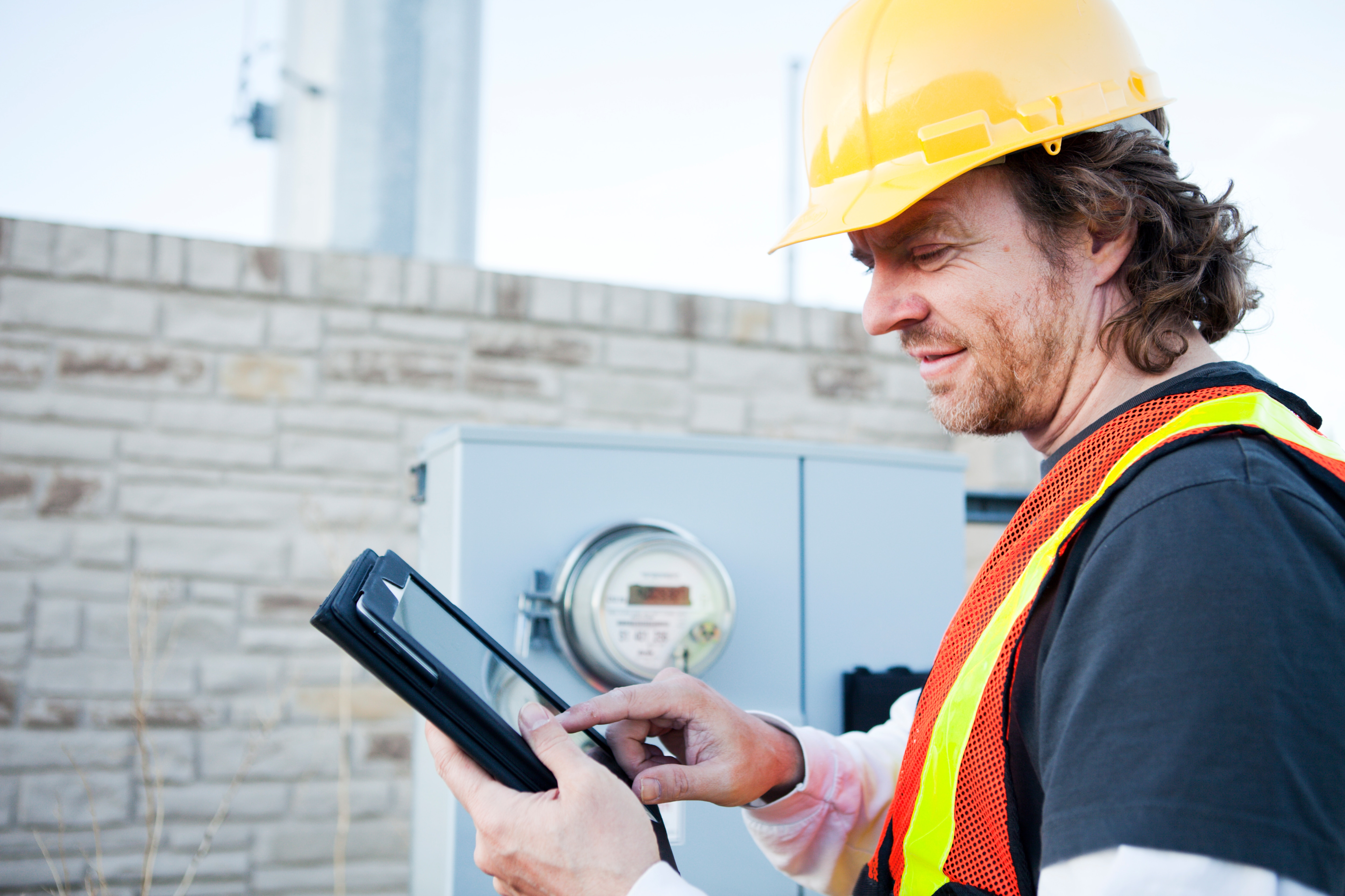 Utility worker on an iPad in front of an electricity meter