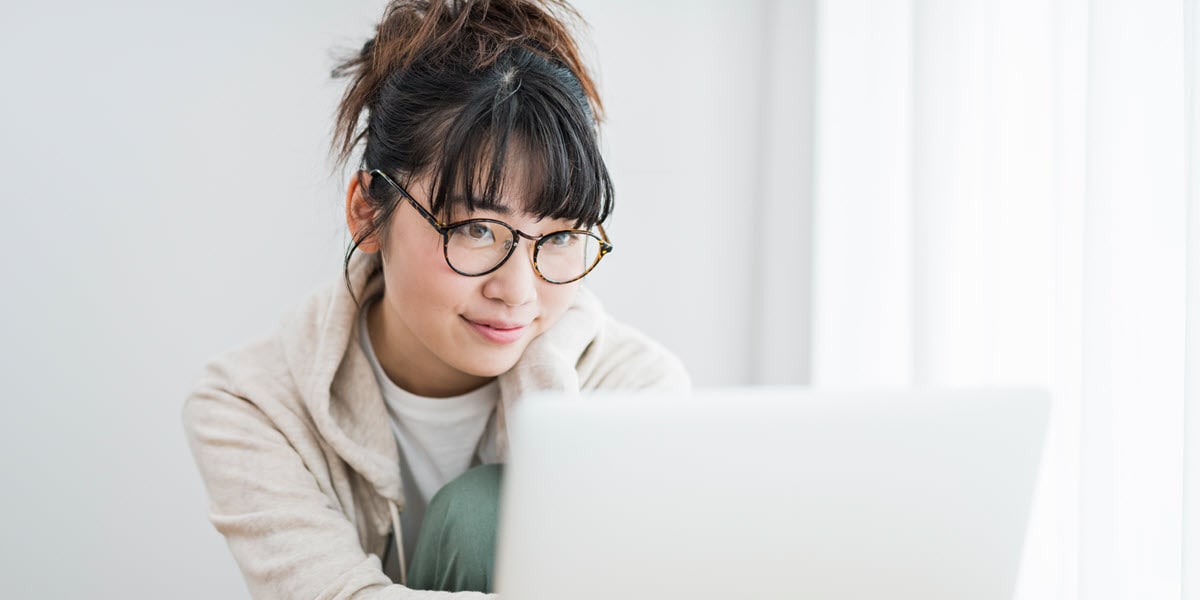 young woman wearing glasses looking at laptop