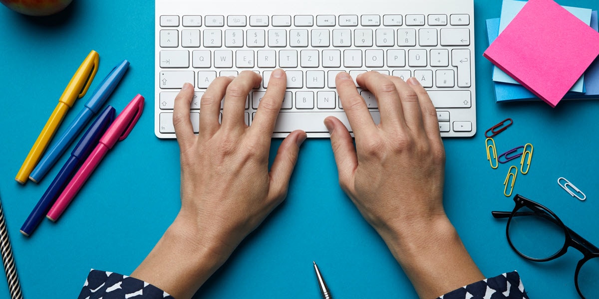 Hands on a keyboard with office supplies