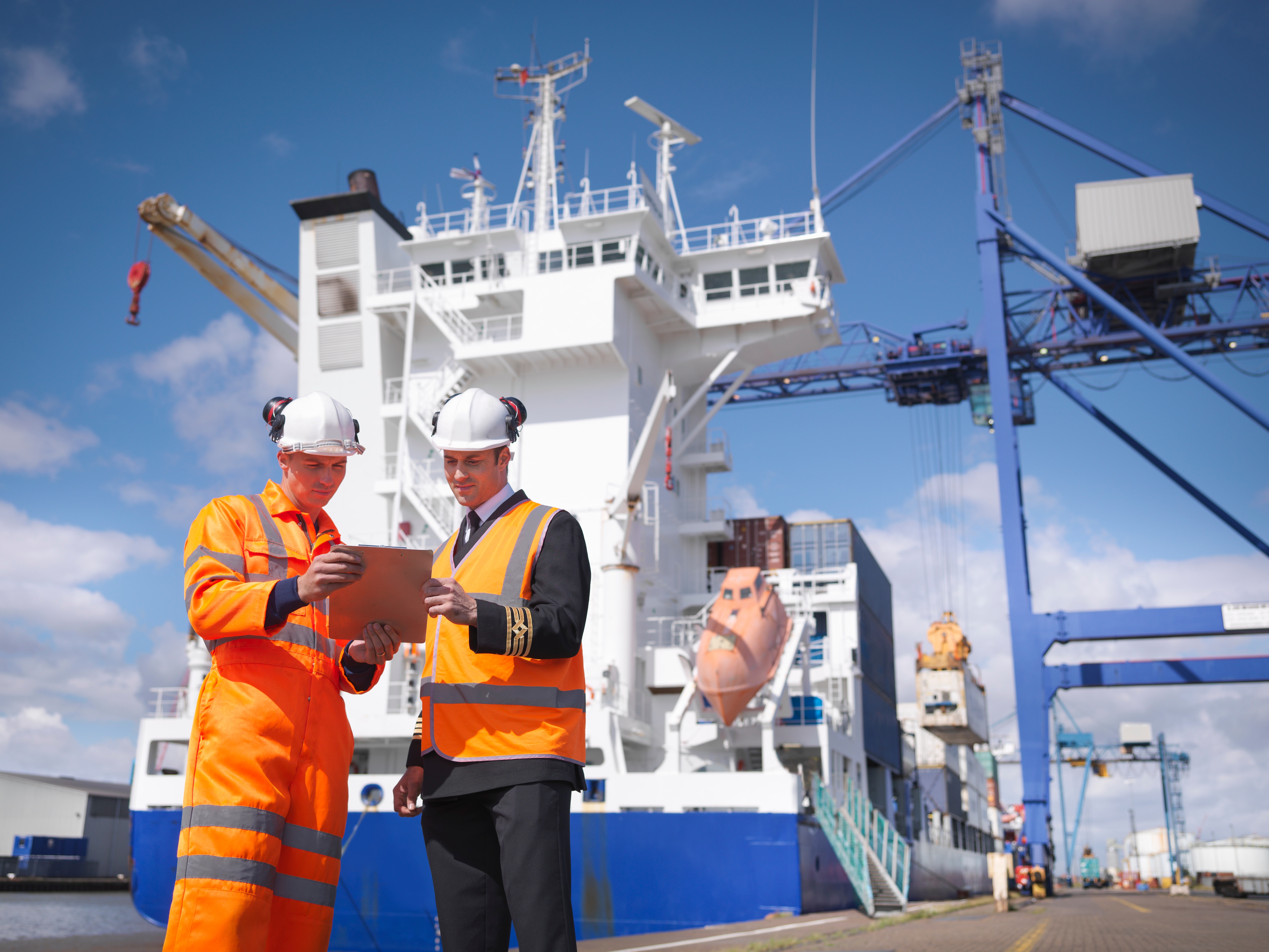 Two port workers looking at a clipboard on a ship
