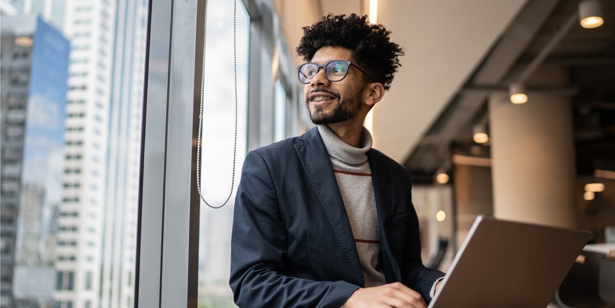man with laptop looking out window