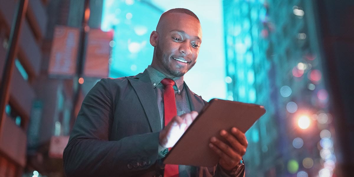 man in suit looking at tablet with city scene in background