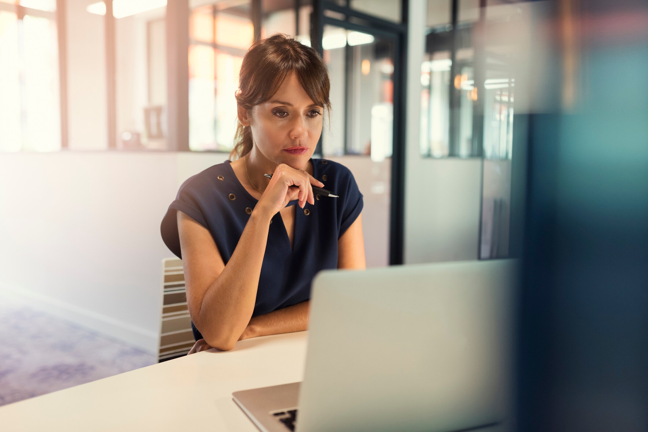 Woman sitting at a desk looking at a computer with a serious face