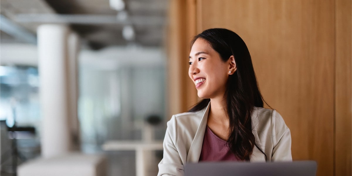 woman at computer looking away and smiling