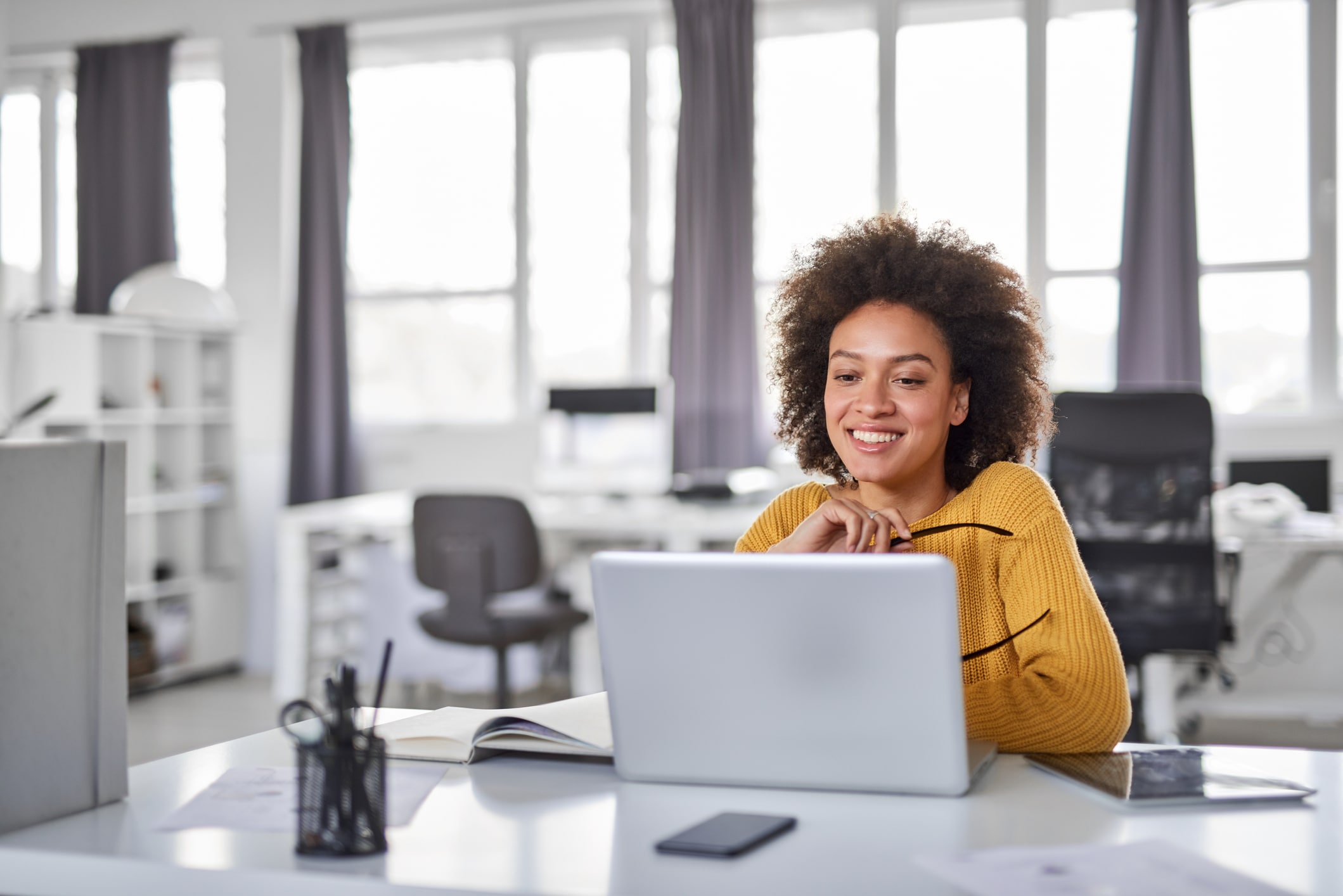 Woman sitting at desk smiling looking at her computer