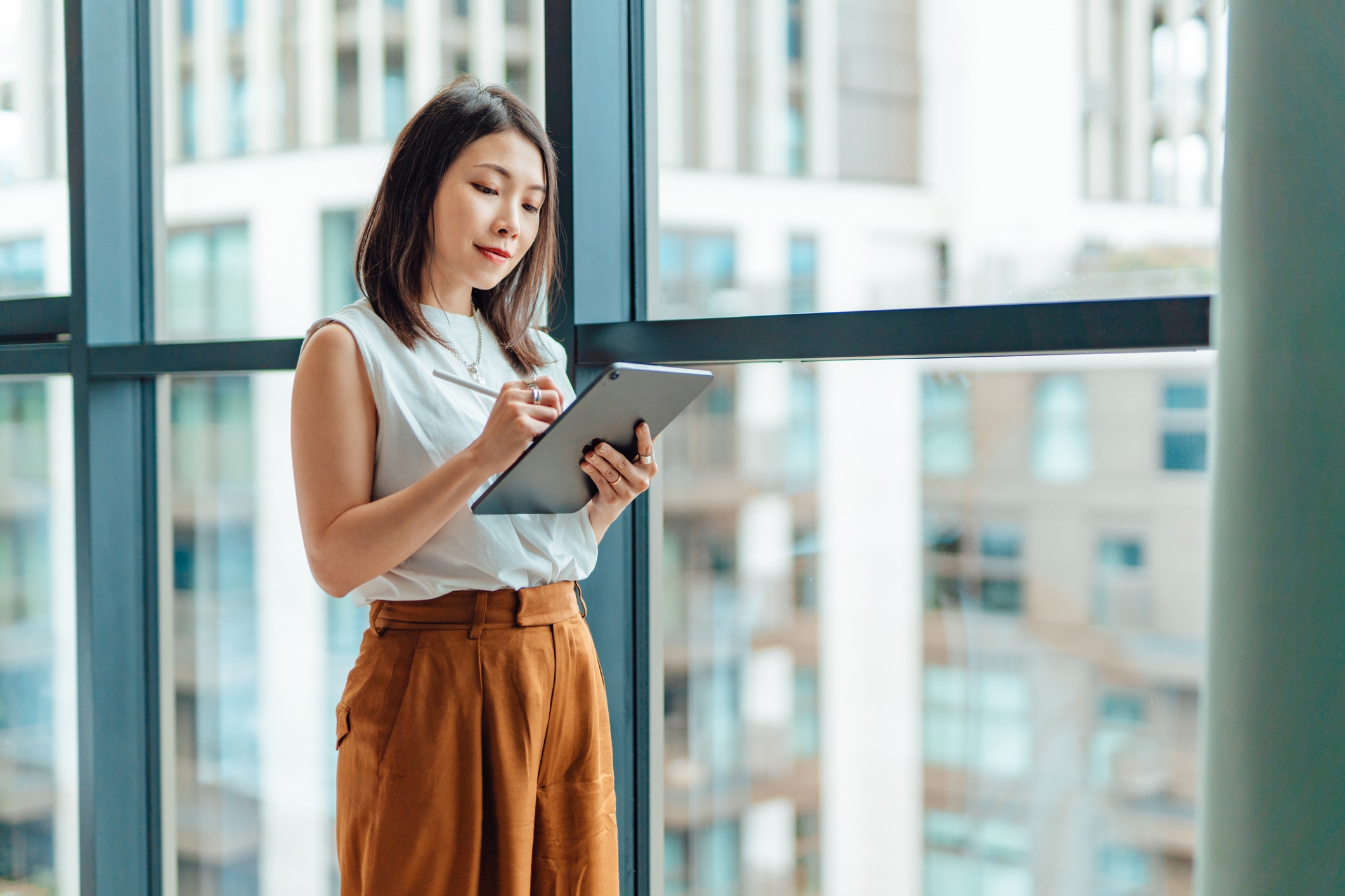 Woman standing by window looking at a tablet