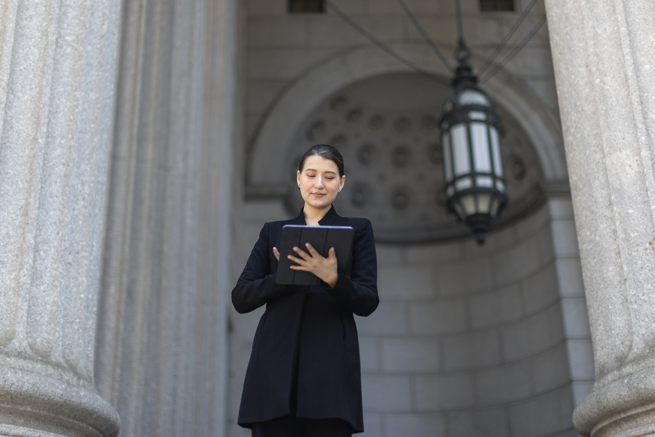 Woman standing in front of a government building looking at a tablet