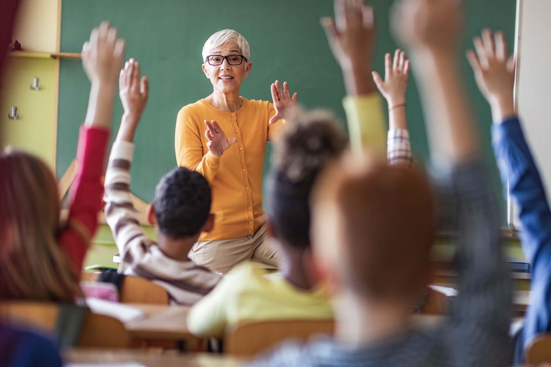 Teacher calling on students with their hands raised in a classroom
