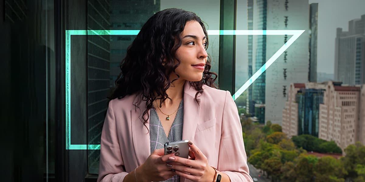 a finance leader smiles confidently while holding a mobile phone and looking out over a city skyline