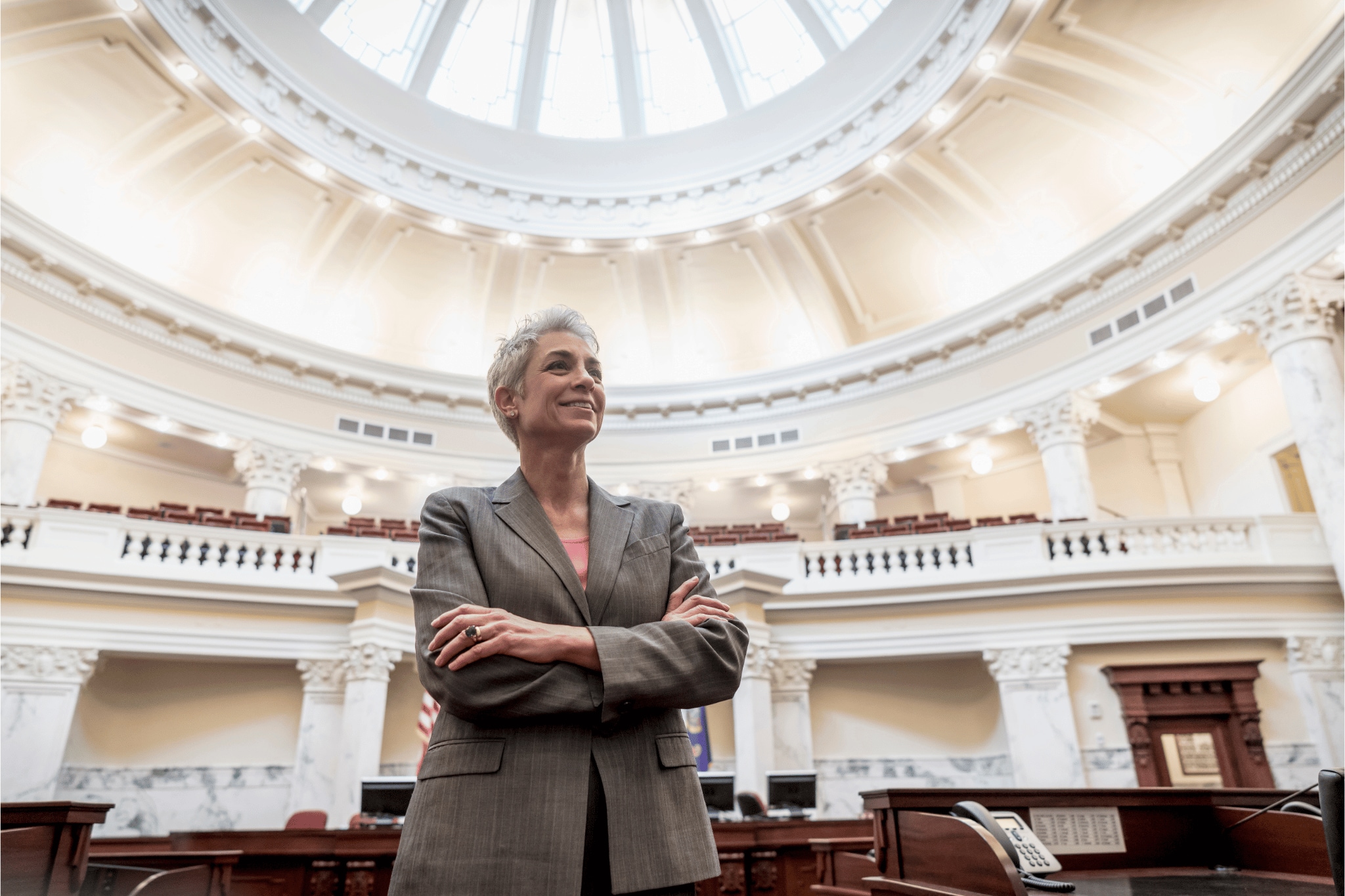 Woman in a capital building with her arms crossed looking at the ceiling