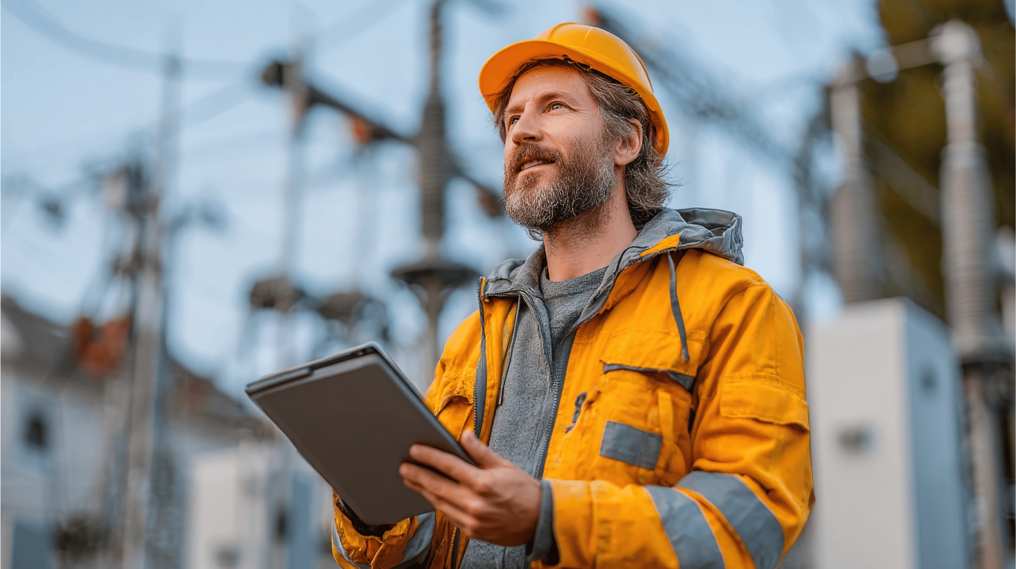 Utilities working holding a tablet looking into the distance