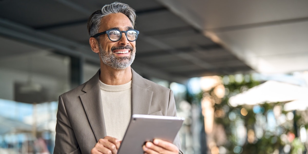 man smiling wearing glasses holding tablet