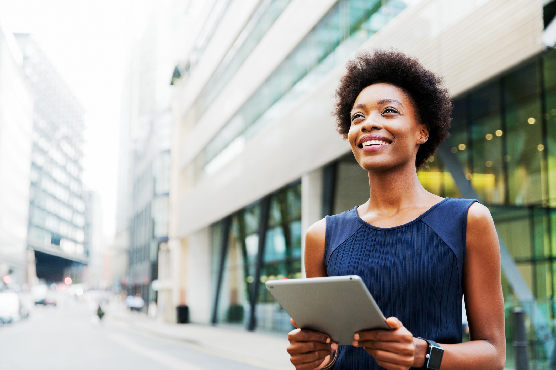 Woman smiling looking into the distance with a tablet in her hand