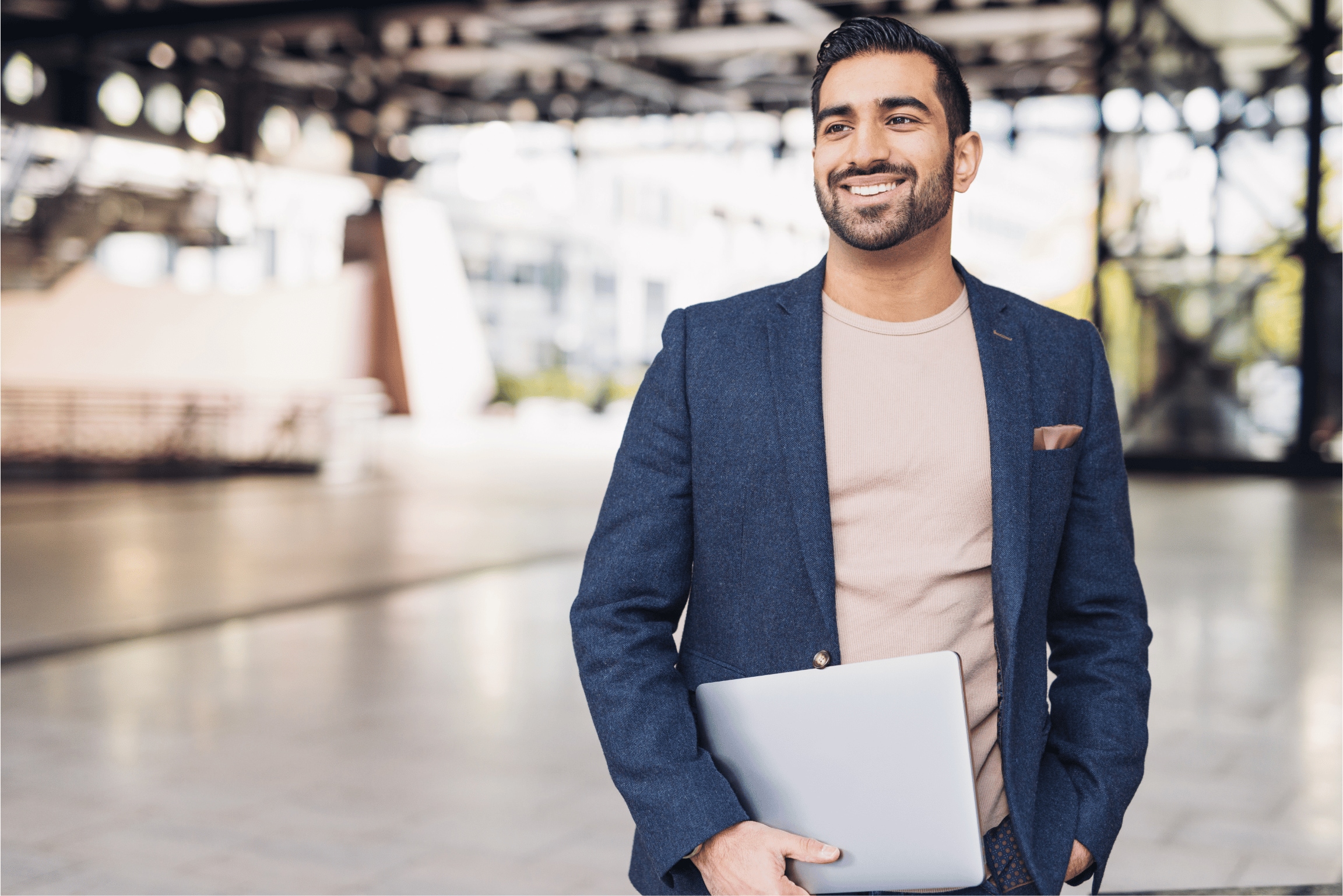 Man standing smiling with a closed computer in his arms