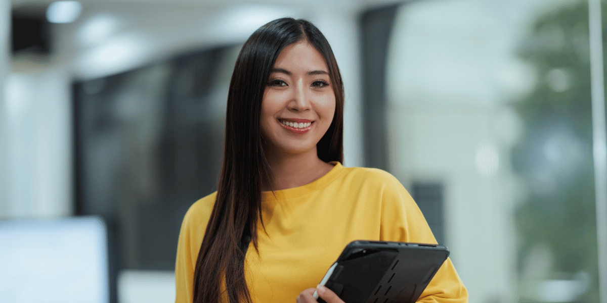 Woman smiling looking at the camera with a closed laptop in her arms