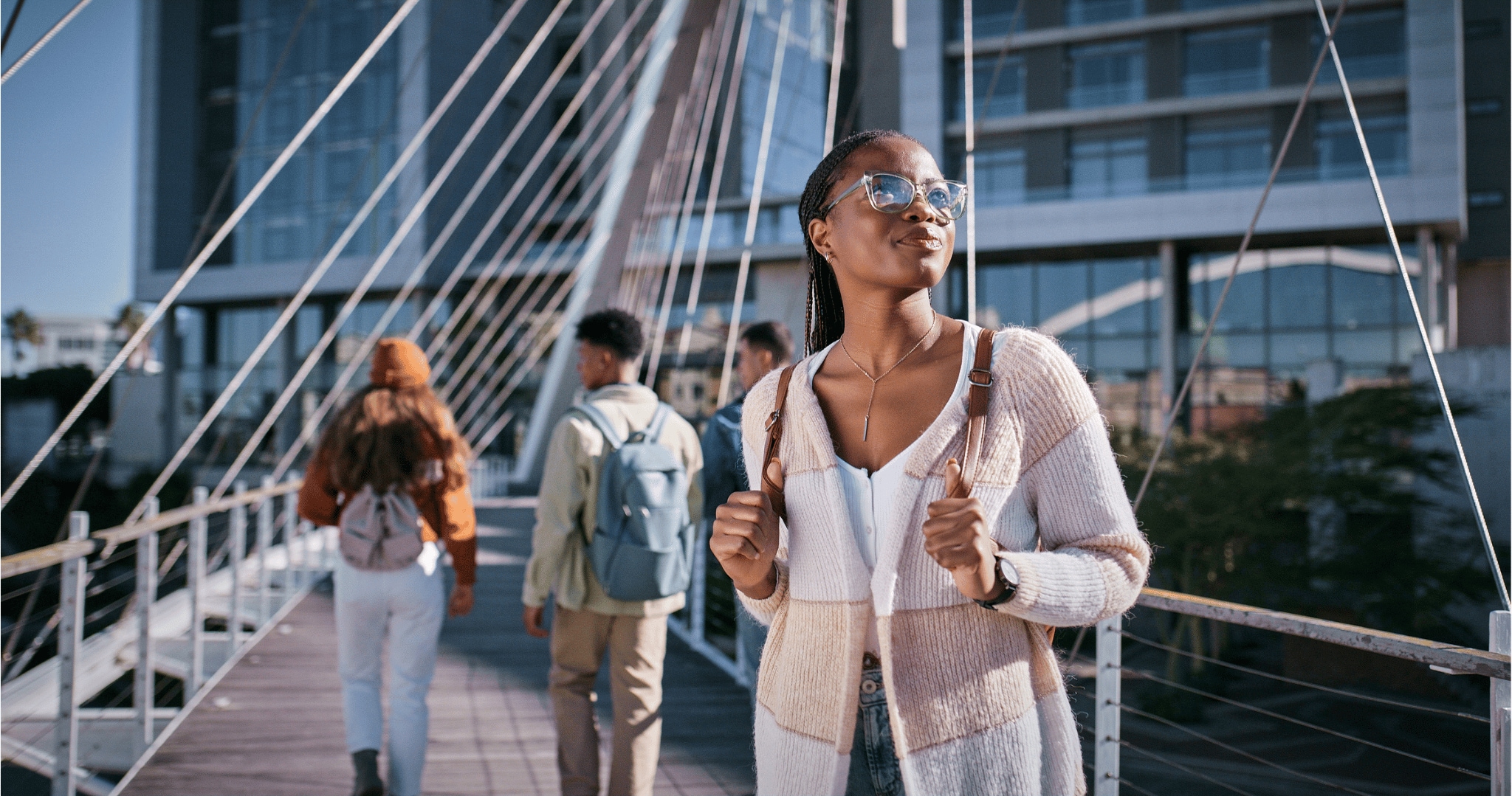 Woman with a backpack on outside looking off into the distance smiling