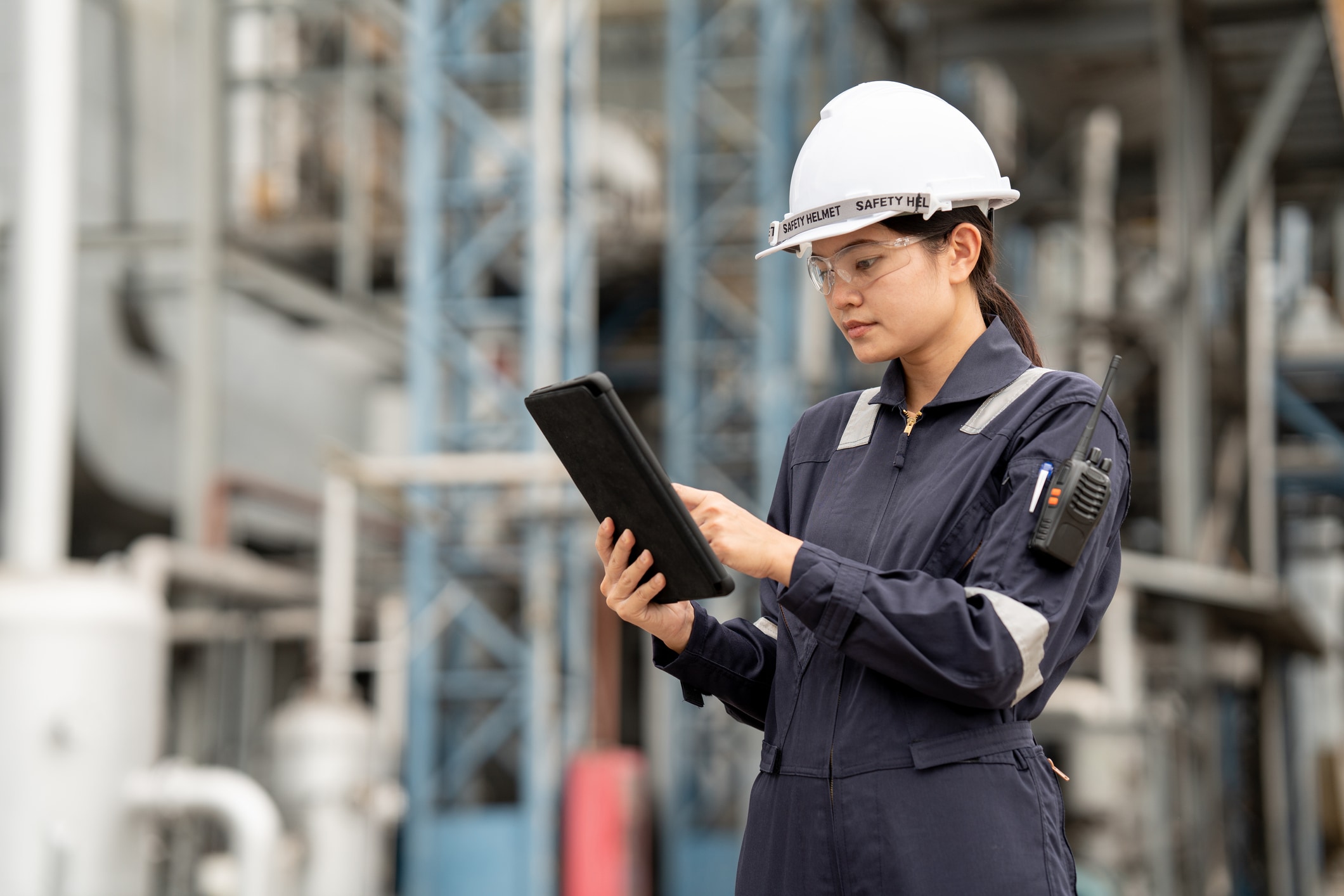 Woman with a hard hat on looking at a tablet in a construction zone