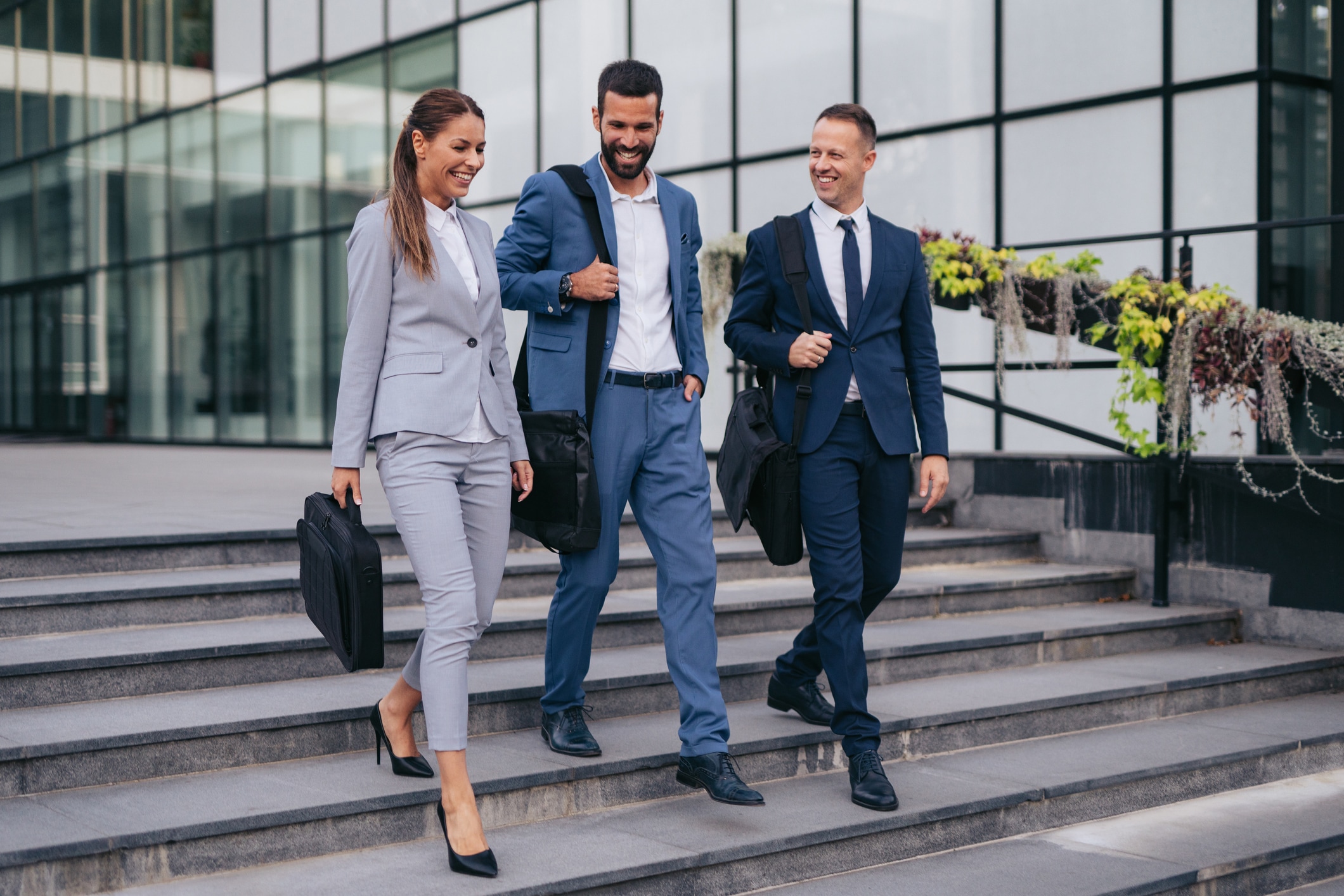 Three professionals in business suits walking down the stairs