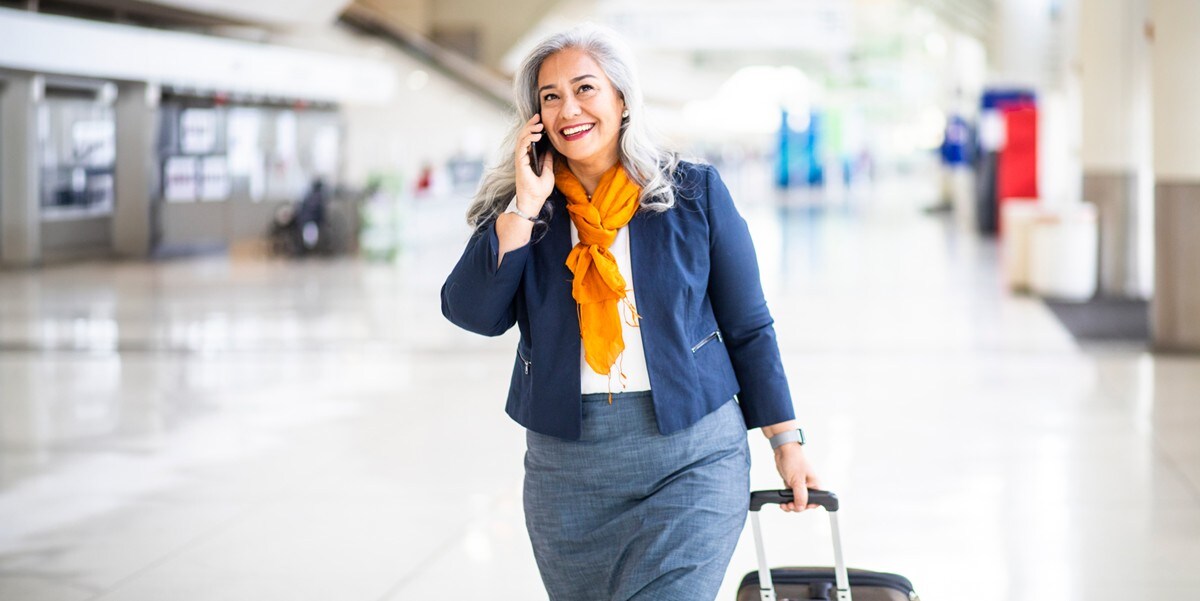 a business traveler walks through an airport with a rolling suitcase