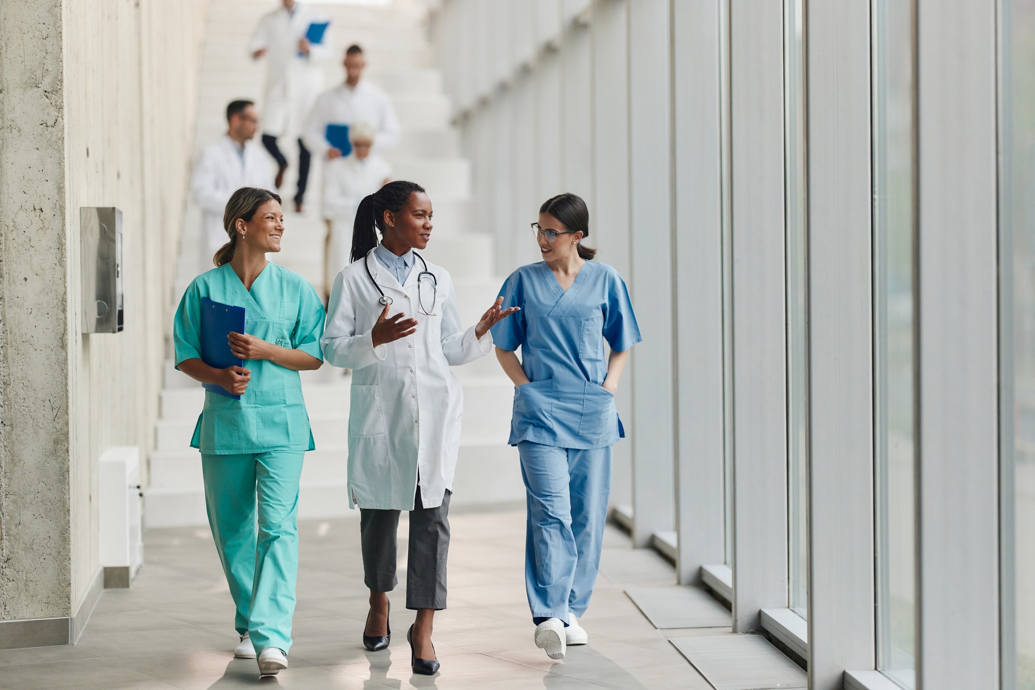 Three healthcare professionals walking down a hallway chatting