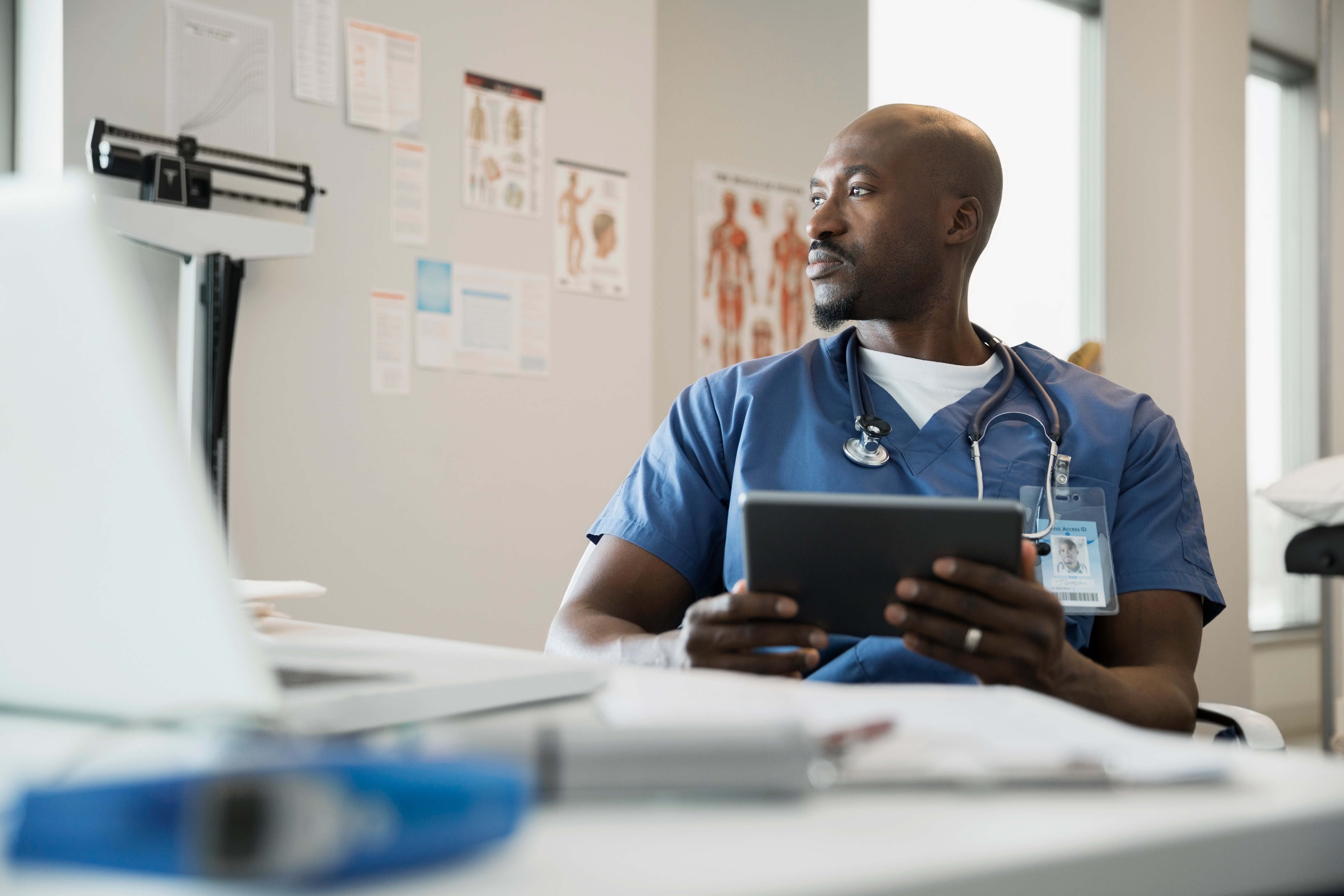 Doctor with a clipboard sitting at a desk looking to the side