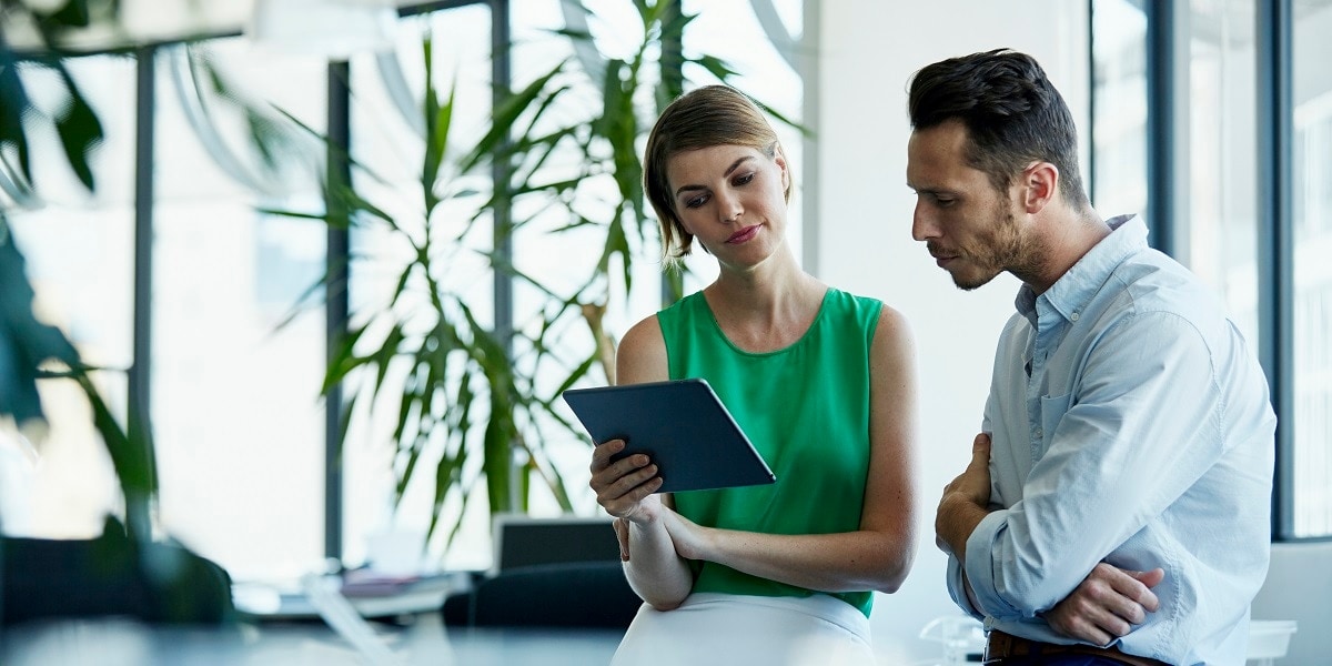 Two business people reviewing information on a tablet in an office setting