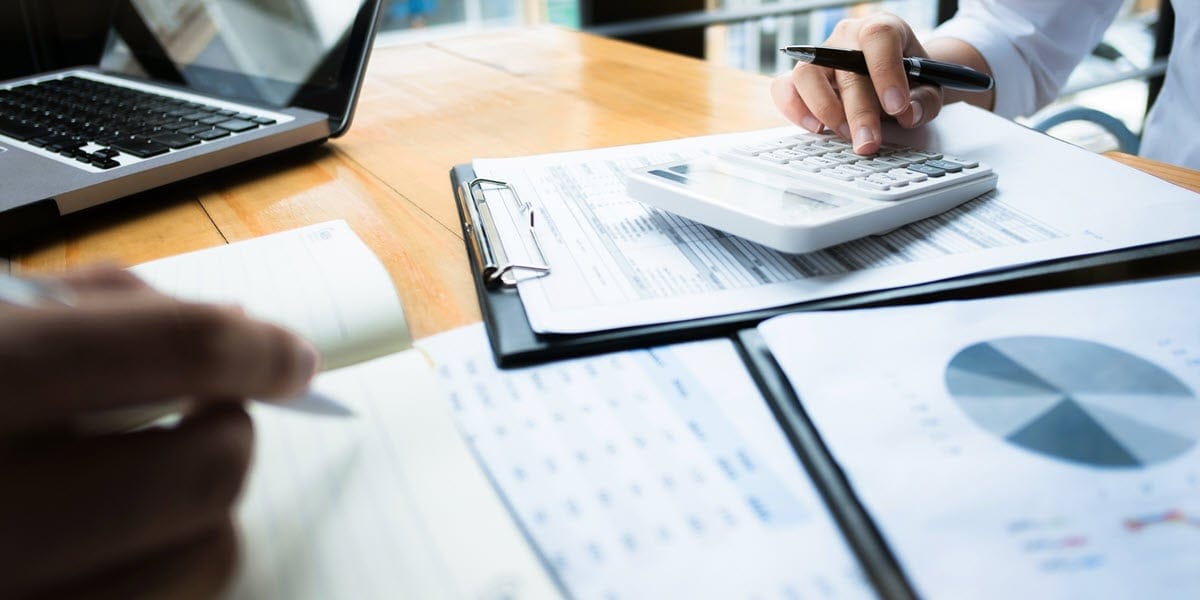 papers, calculator, and pens in hands on table