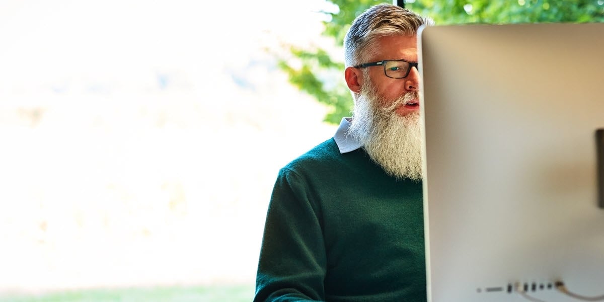 man with white beard and glasses looking at computer screen