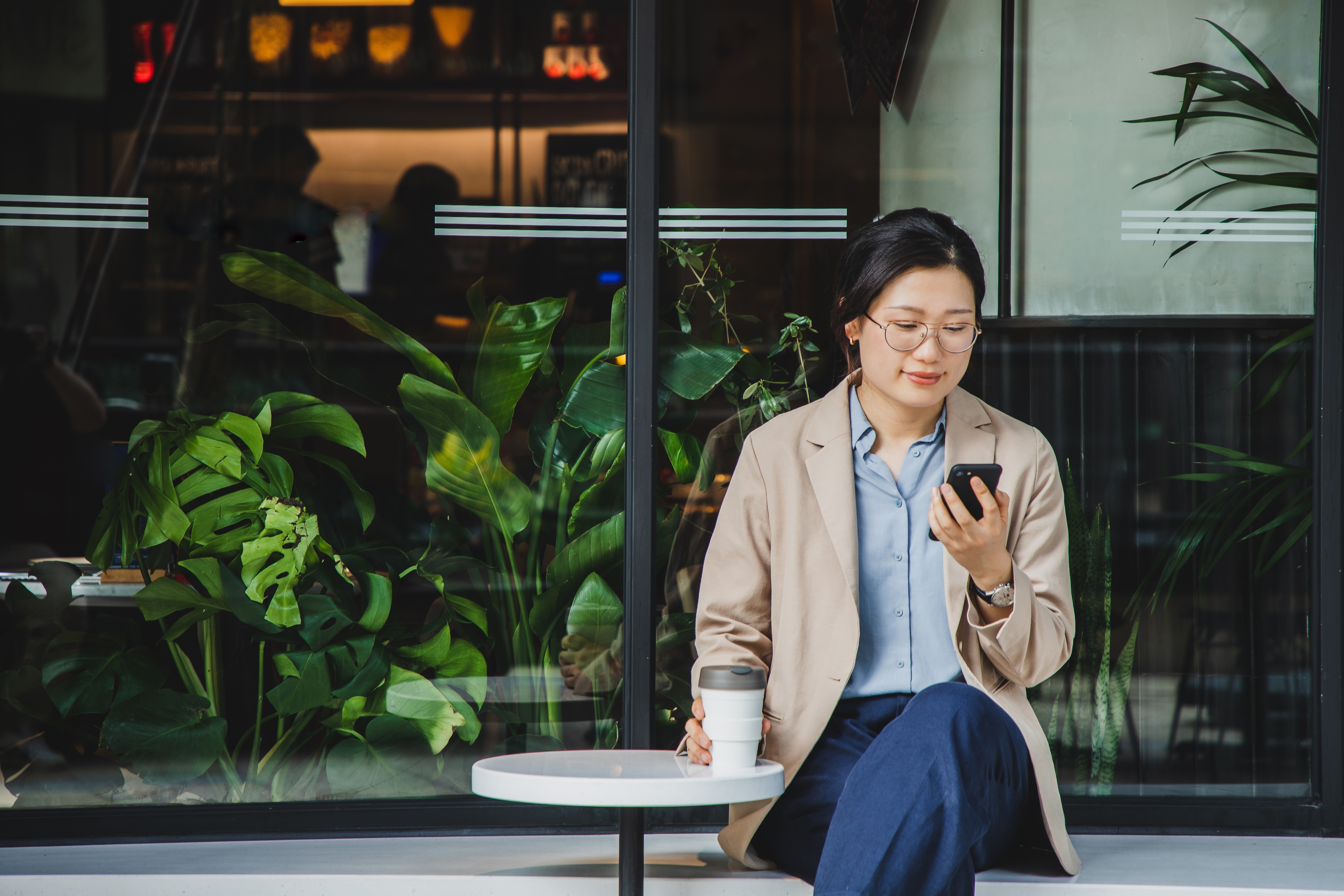 asian woman in brown jacket reading her phone