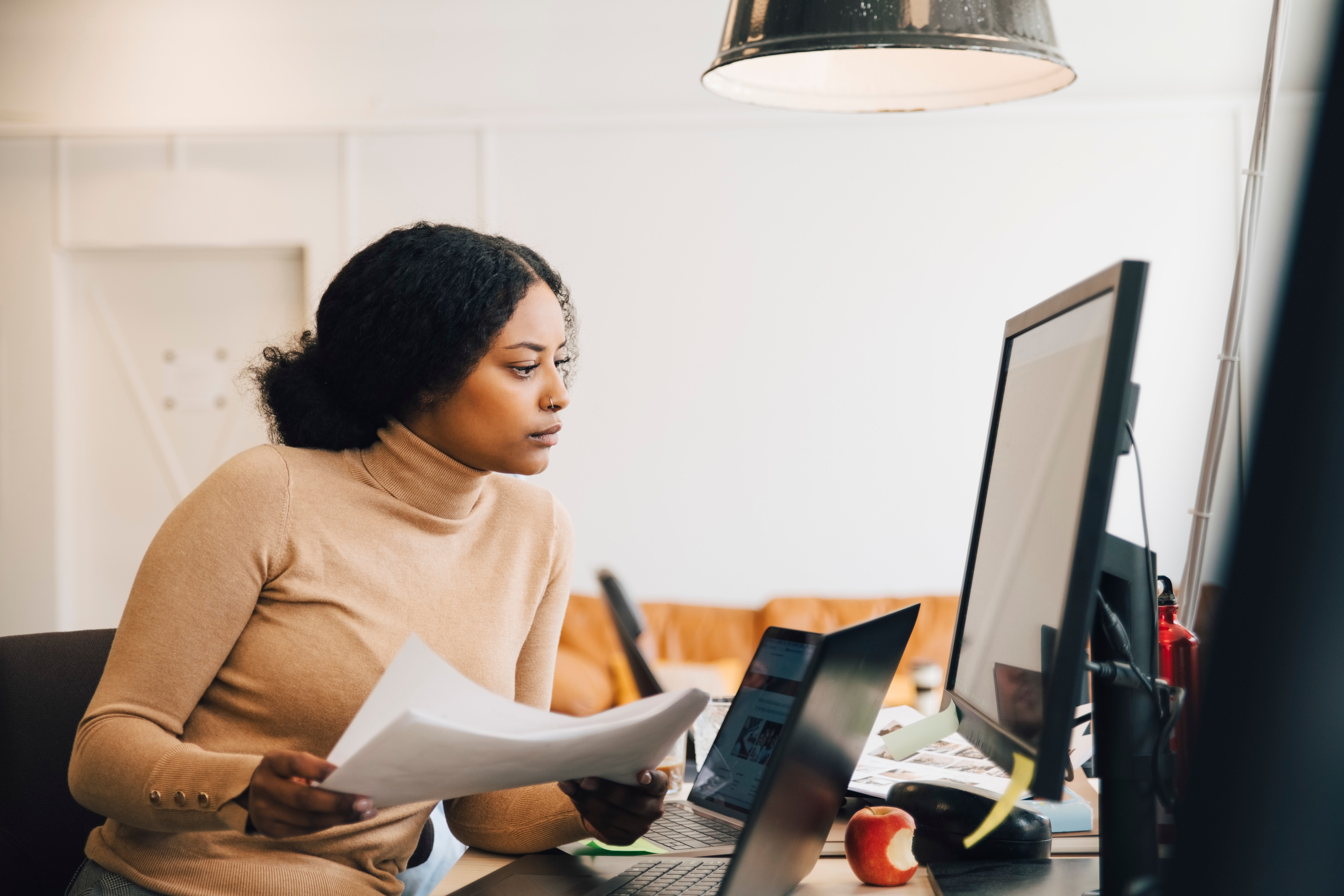 Woman looking at computer with papers in her hand