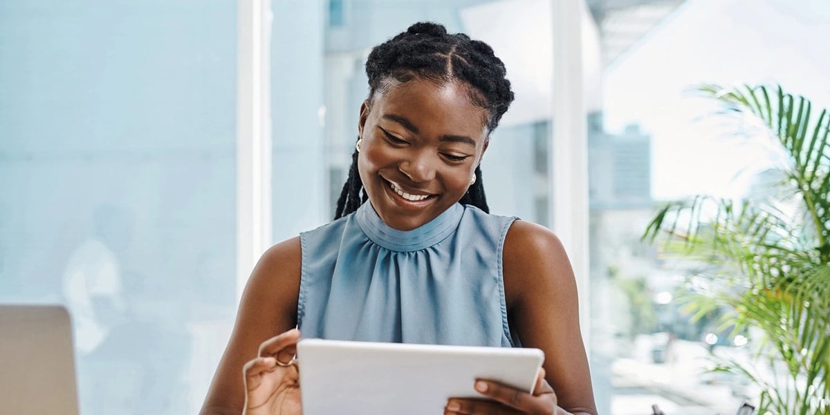 woman smiling while looking at tablet