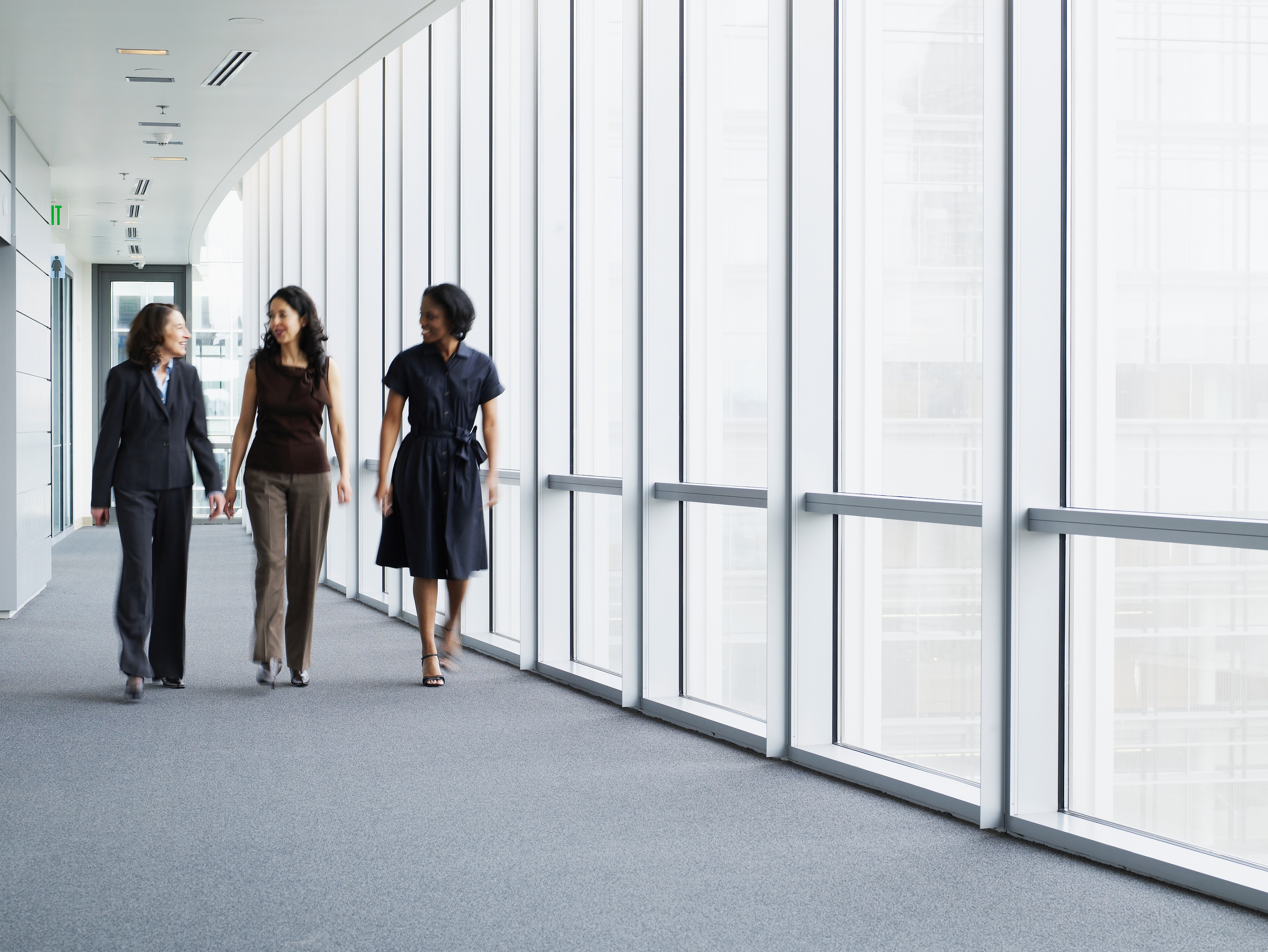 Three women walking down a hall discussing business