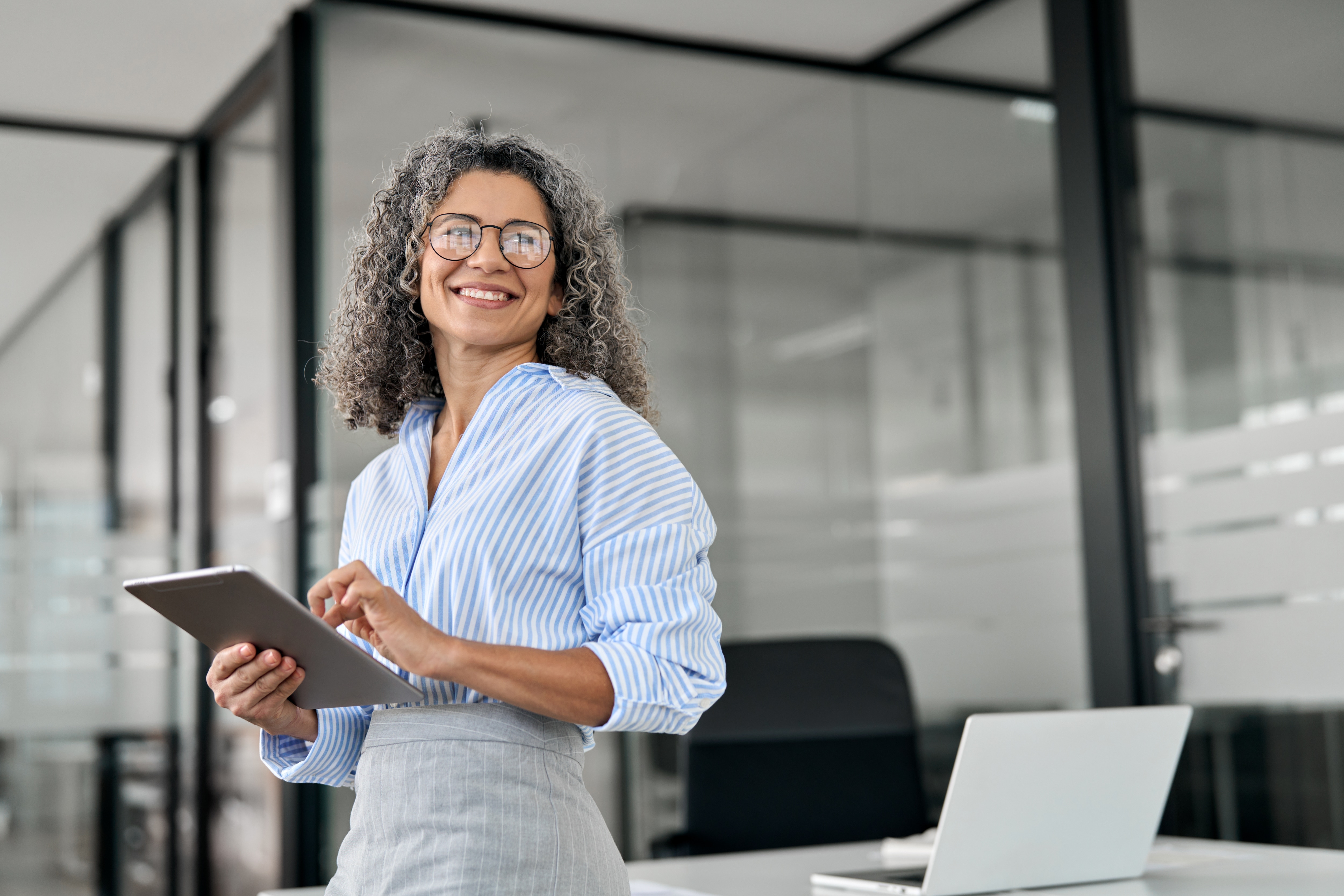 Woman smiling looking to the side with an ipad in her hand