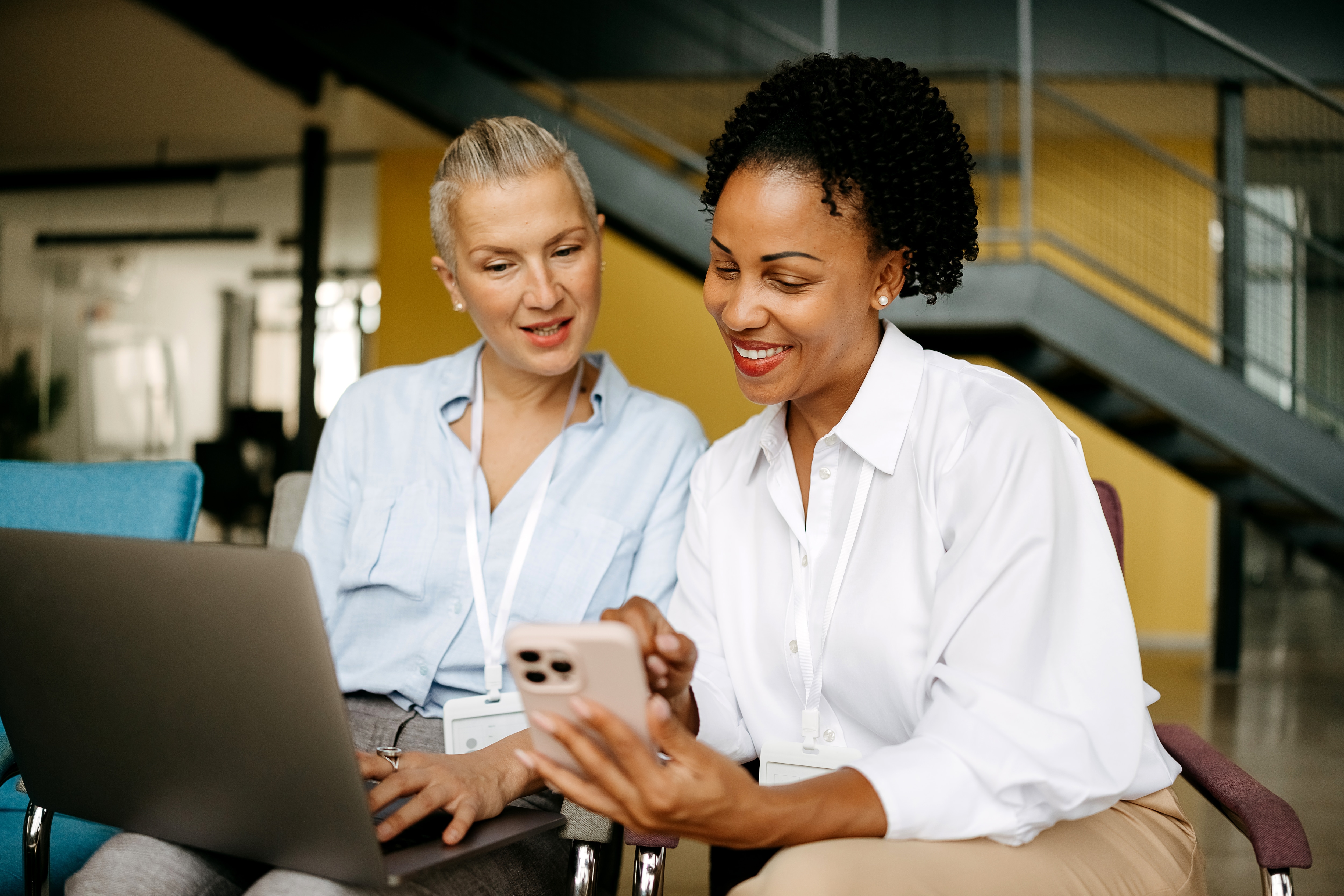 two business woman looking at their digital devices