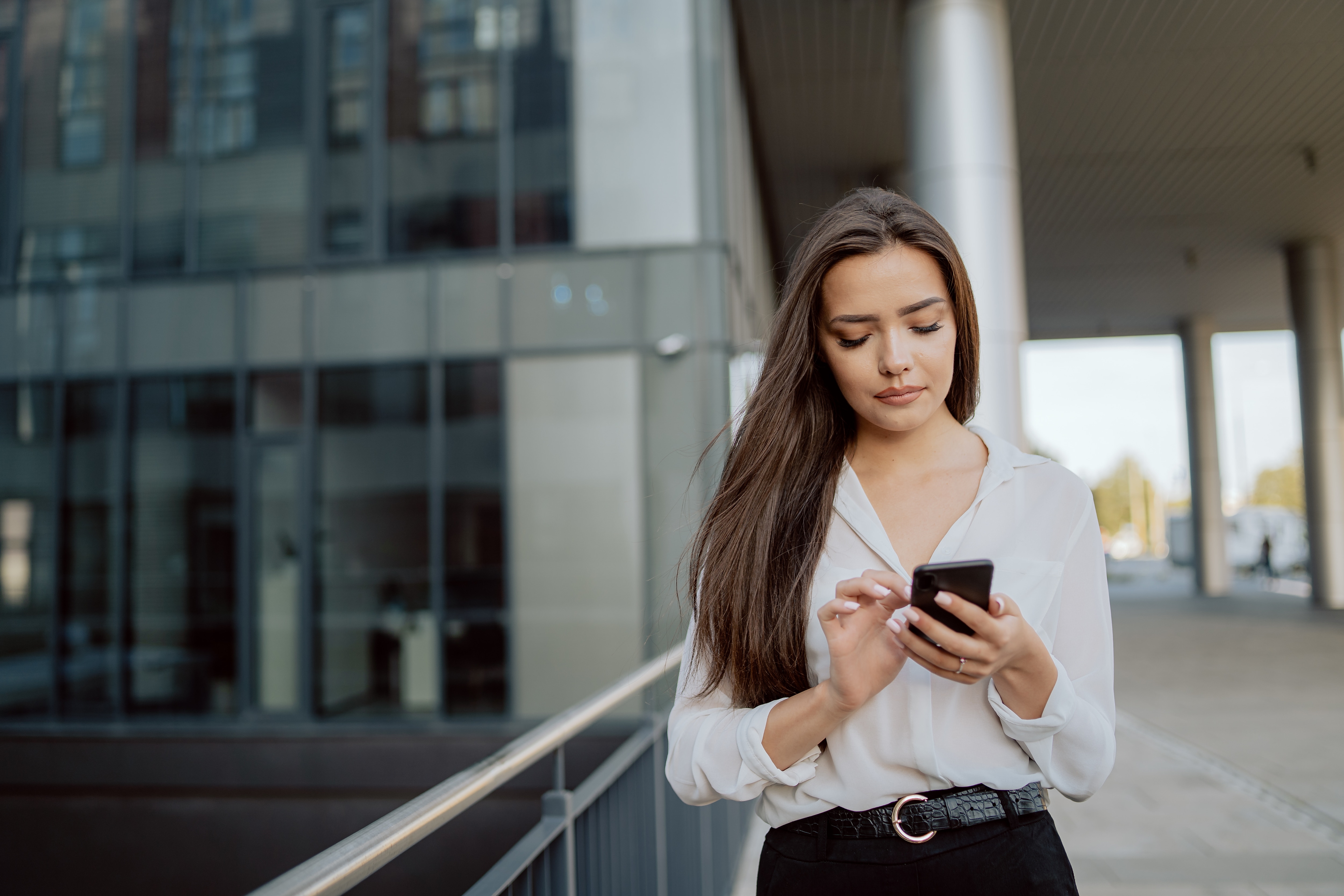 Woman walking out of building reading her phone