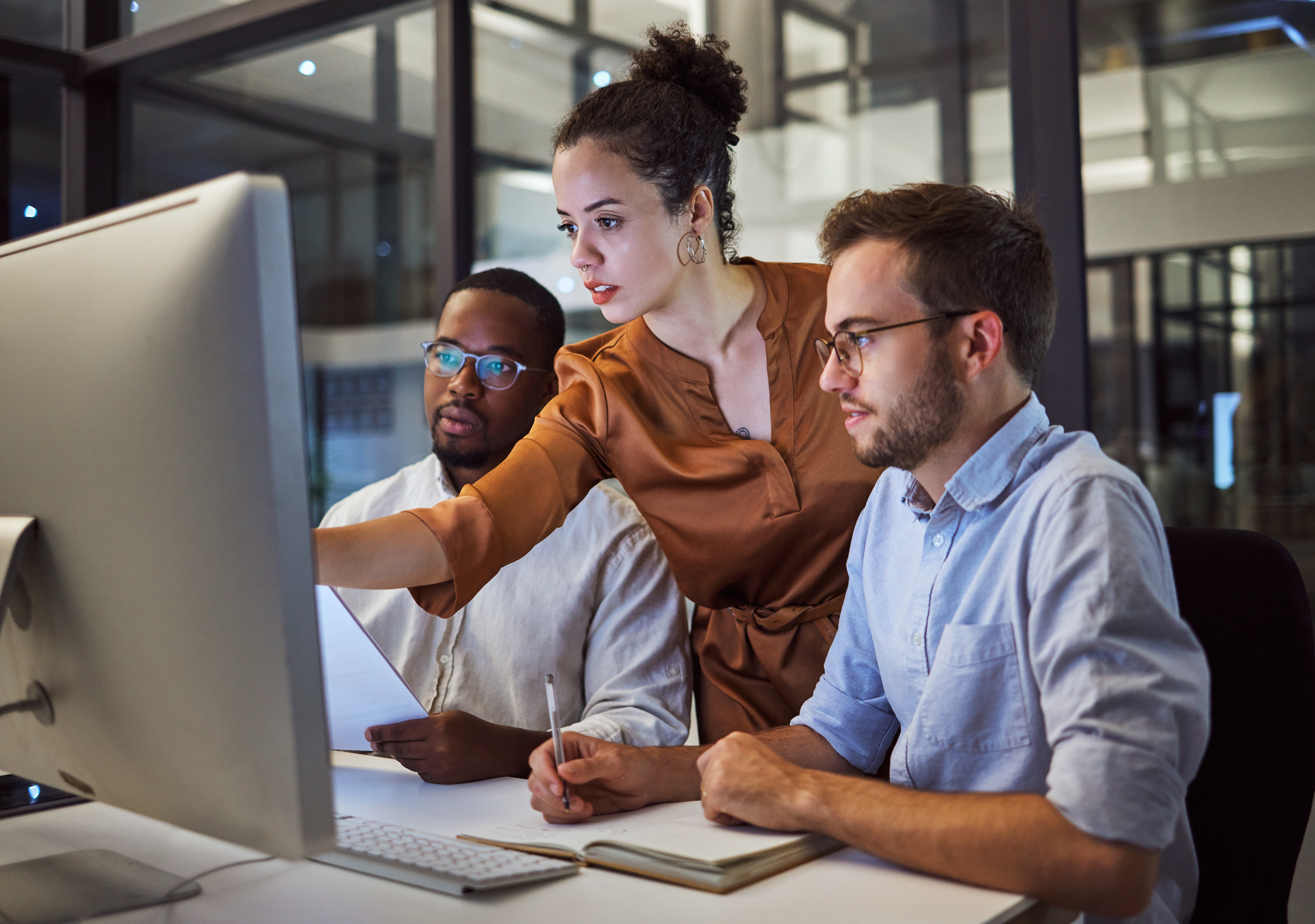 Three people looking at a computer screen debating information they see