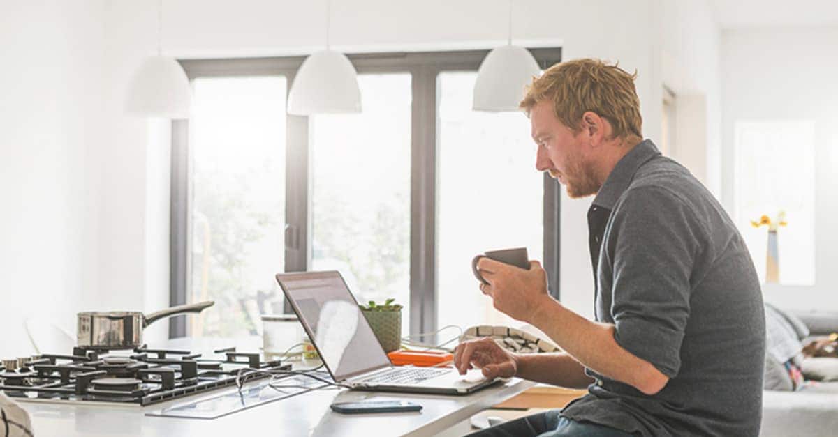 Man uses computer while sitting at kitchen island