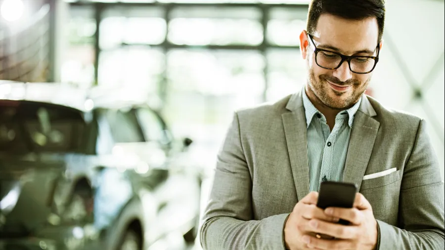 man looking at phone with rental car