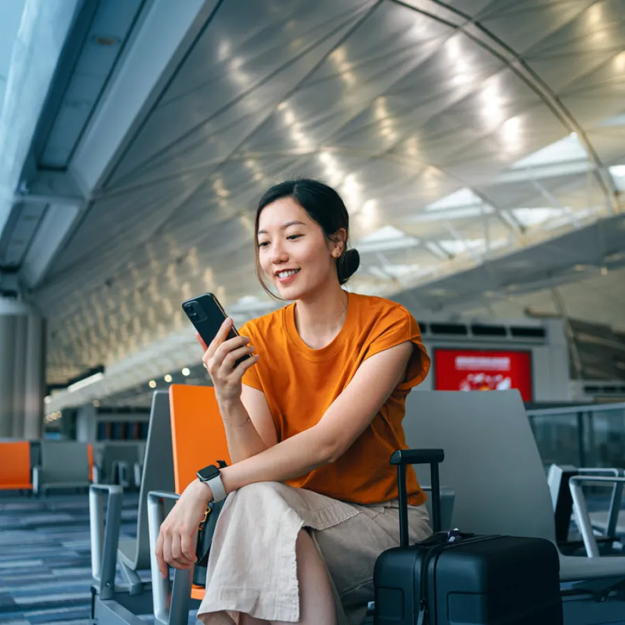 Woman sitting in airport looking at phone