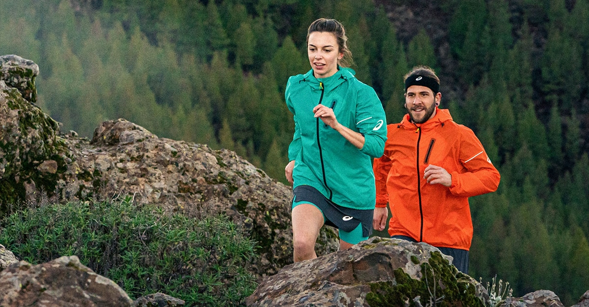 Man and woman run up a mountain wearing ASICS apparel