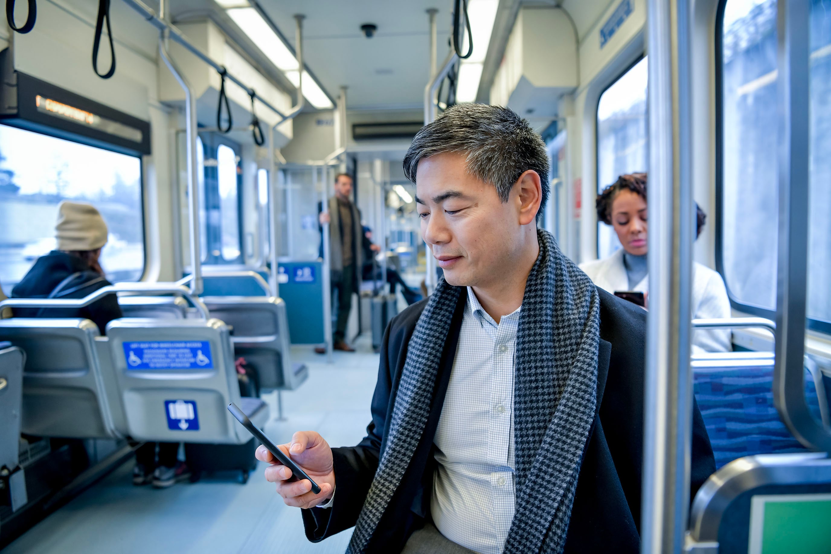 Man riding the subway looking at his phone