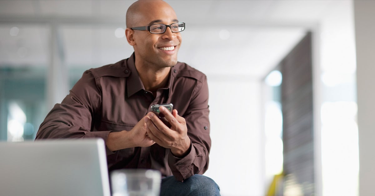 Man using smartphones smiles while looking into the distance