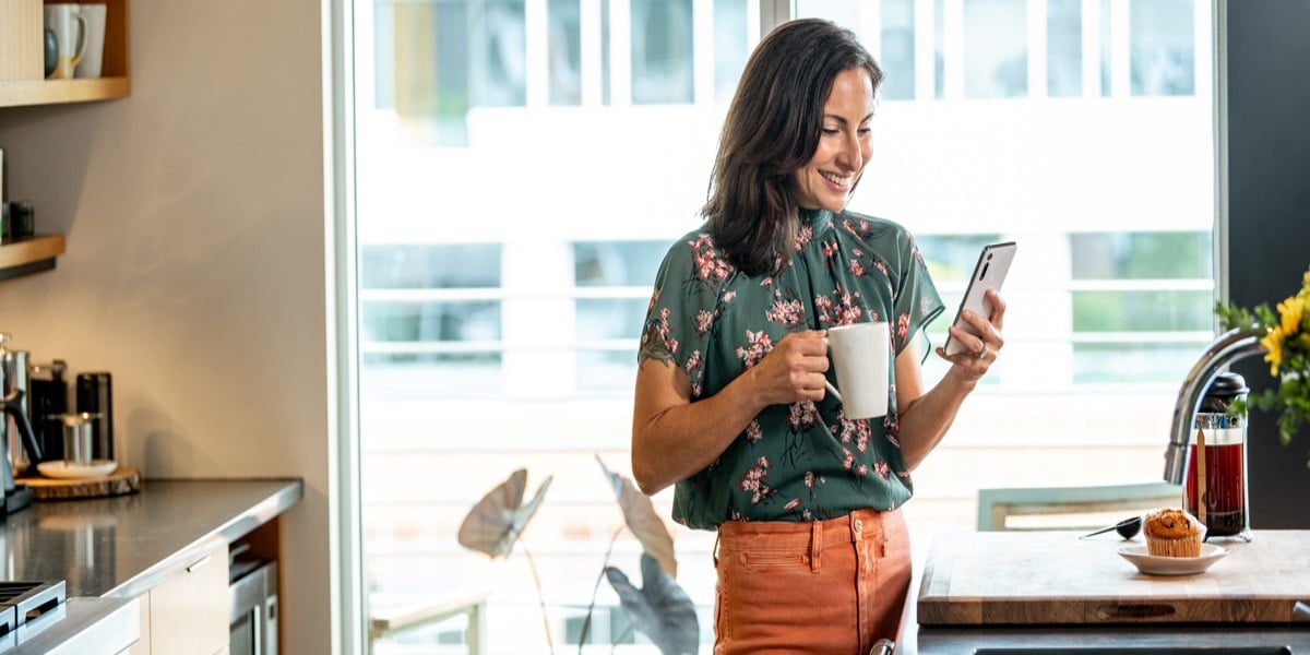 Woman with a cup of coffee in one hand and smart phone in the other